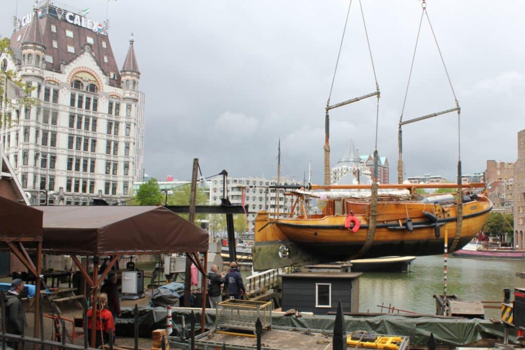 Houten zeilschip wordt met de kraan op de wal gezet