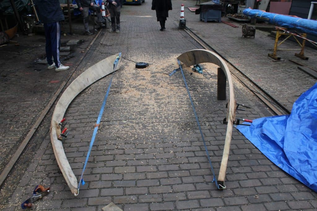 Gebogen houten spanten liggen klaar op het werfterrein