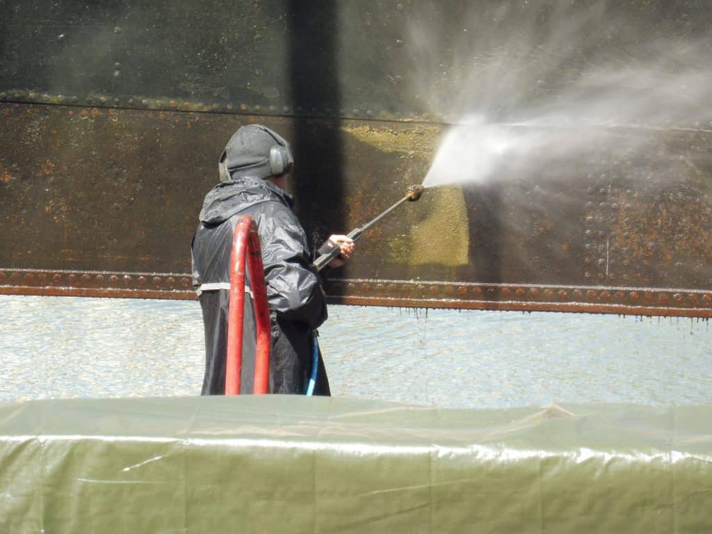 Schoonspuiten van een scheepsromp met de hogedrukspuit